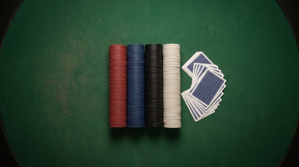 Four stacks of casino chips and a fanned deck of cards on green felt