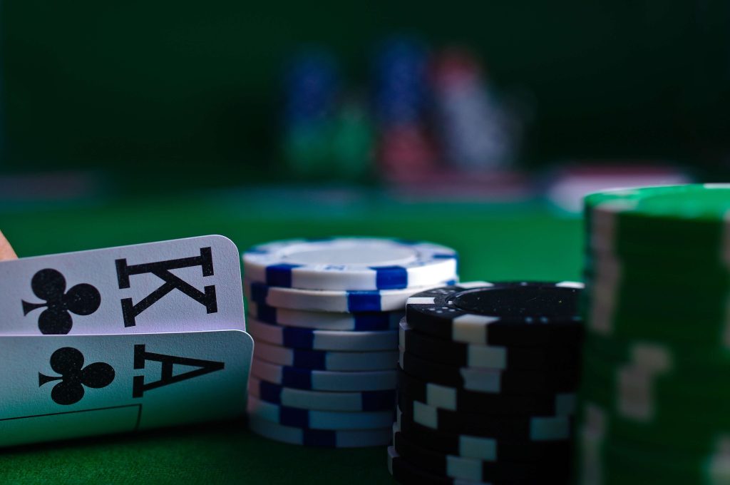 
White and black poker chips next to two playing cards.