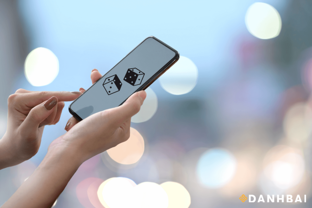 Một bàn tay cầm điện thoại thông minh hiển thị hai viên xúc xắc.