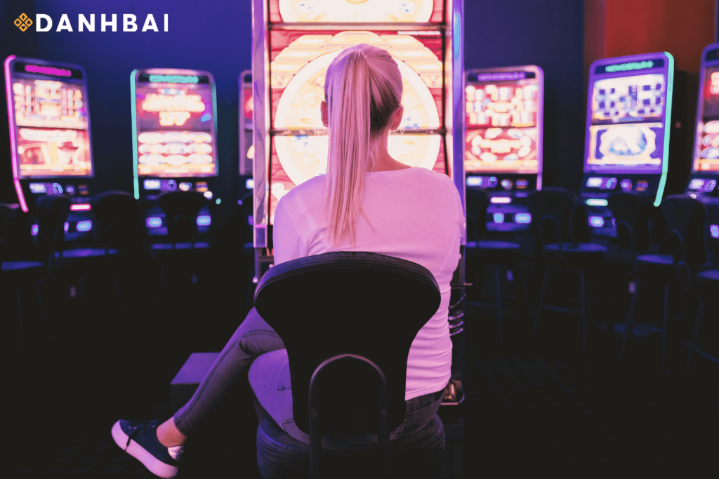 Một người ngồi bên cạnh máy đánh bạc trong sòng bạc.